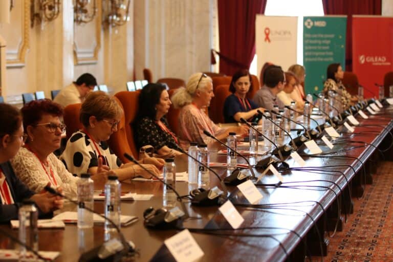 Participanți la conferință despre sănătate și prevenție, în sală elegantă.