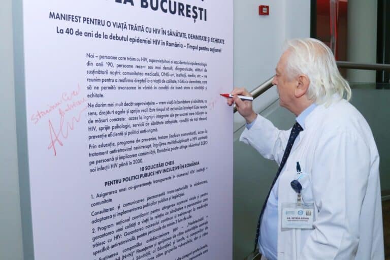 Medic semnează un manifest despre HIV pe un panou informativ.