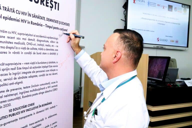 Medic scriind pe panou informații despre HIV și prevenție în România.